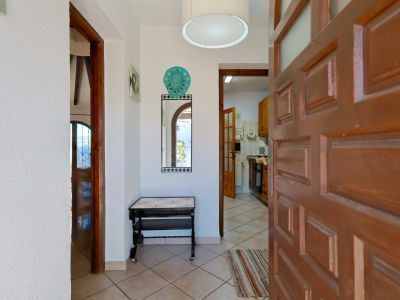 Bright entryway featuring a decorative mirror and a solid wood door ajar, leading to the kitchen.