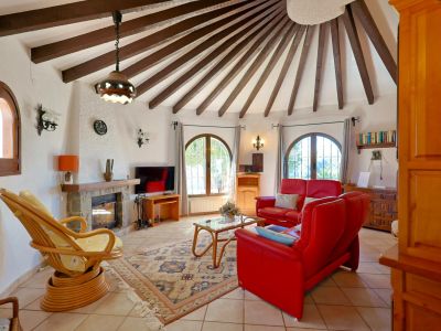 Circular living room featuring exposed wood beams and a stone fireplace.