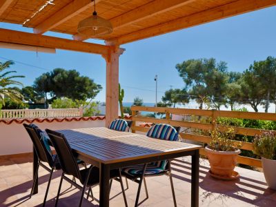 Covered terrace with dining table and views of the Mediterranean Sea.