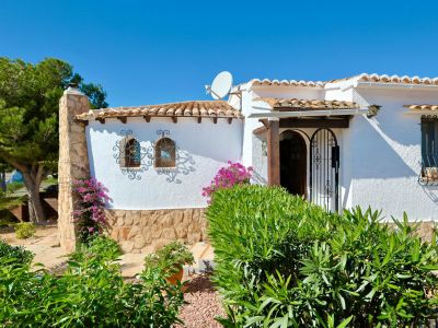 Facade of a Mediterranean villa with stone details, roof tiles, and ornamental ironwork.