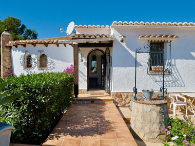 Front view of the villa featuring a decorative stone well and terracotta tiled walkway.