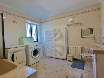 Functional bathroom featuring a washer, dryer, and a spacious white louvered cabinet.