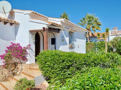 Mediterranean villa facade with bougainvillea and arched wood entrance.