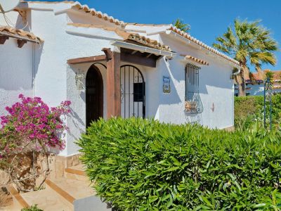 Mediterranean villa facade with bougainvillea and wood details.