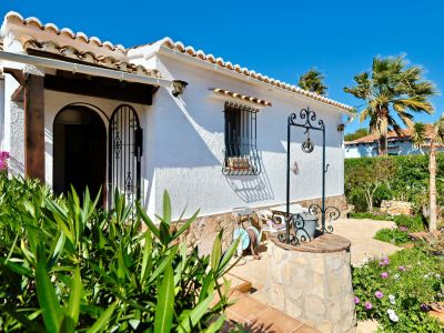 Mediterranean villa facade with decorative well and lush garden.