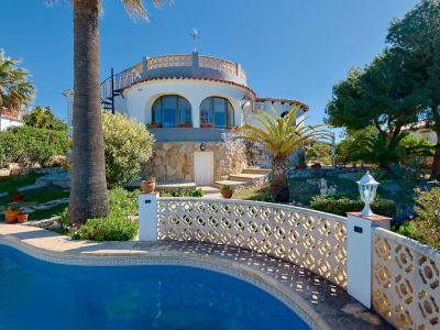 Pool view with lattice railing and stone facade of the villa in Jávea.