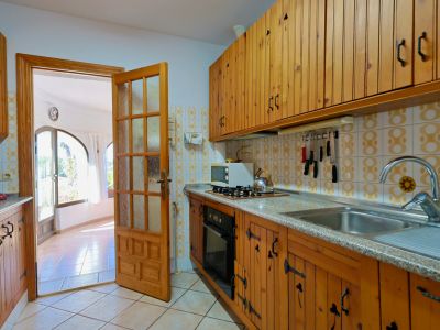 Rustic kitchen featuring wood cabinetry and access to a bright living room with large windows.