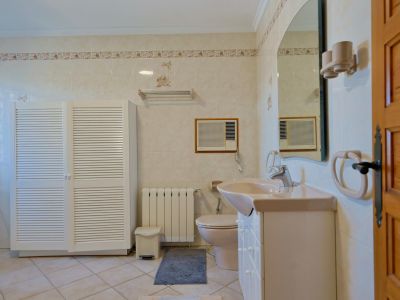 Tiled bathroom featuring a white louvered cabinet and a beige countertop sink.