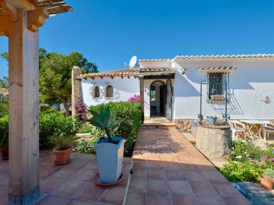 Villa entrance featuring a decorative well, garden, and tiled terrace.
