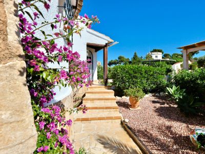 Villa entrance featuring fuchsia bougainvillea and gravel garden.