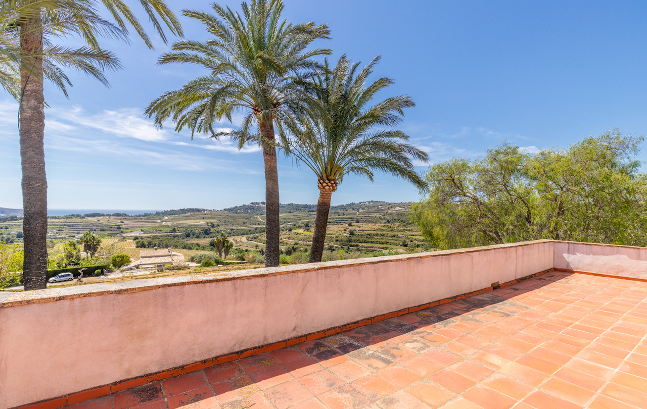 Elevated terrace featuring traditional terracotta tiling and panoramic views over terraced vineyards towards the Mediterranean coast and horizon.