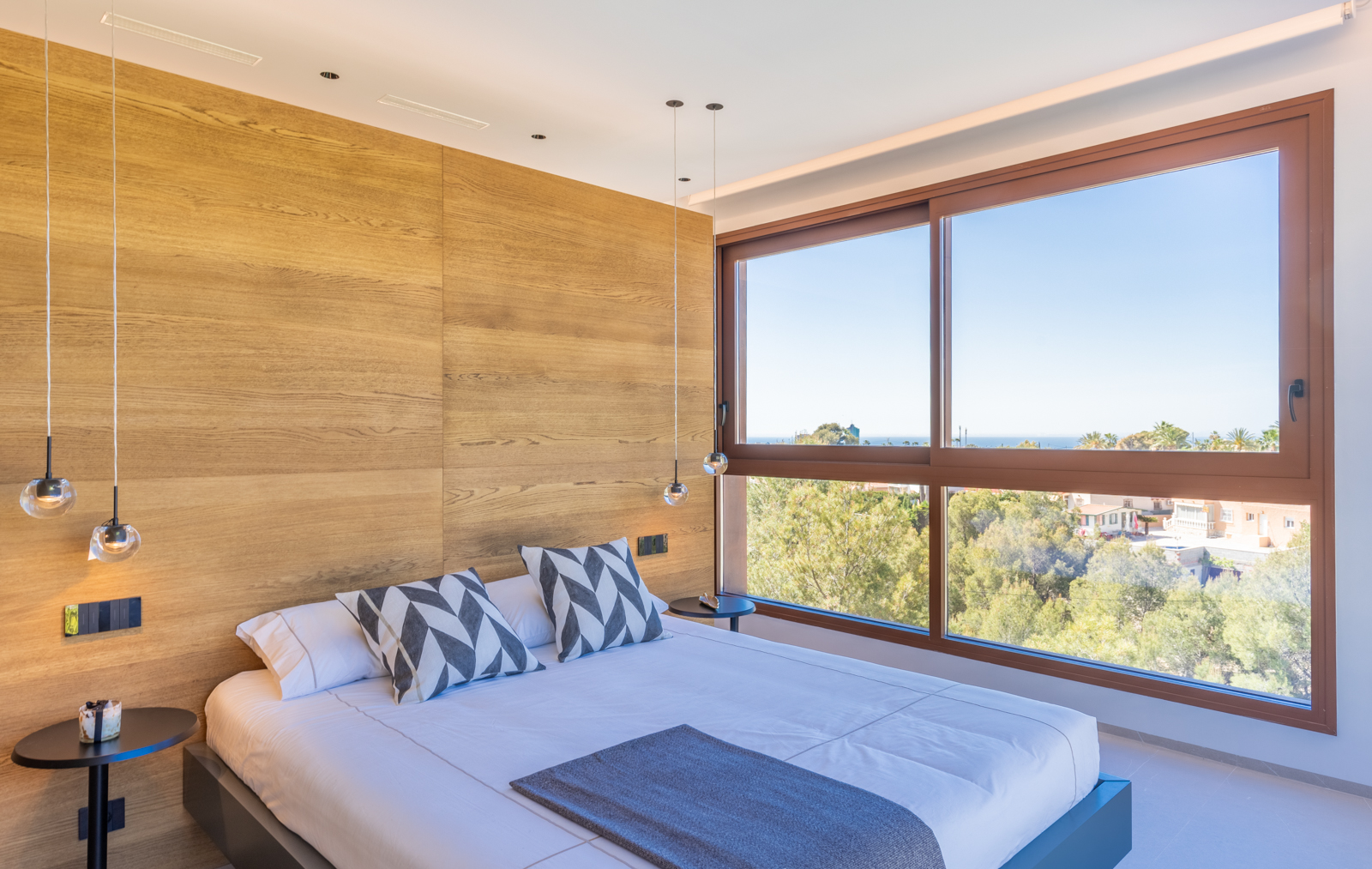 Bedroom featuring a light wood wall, spherical pendant lights, and exterior views.