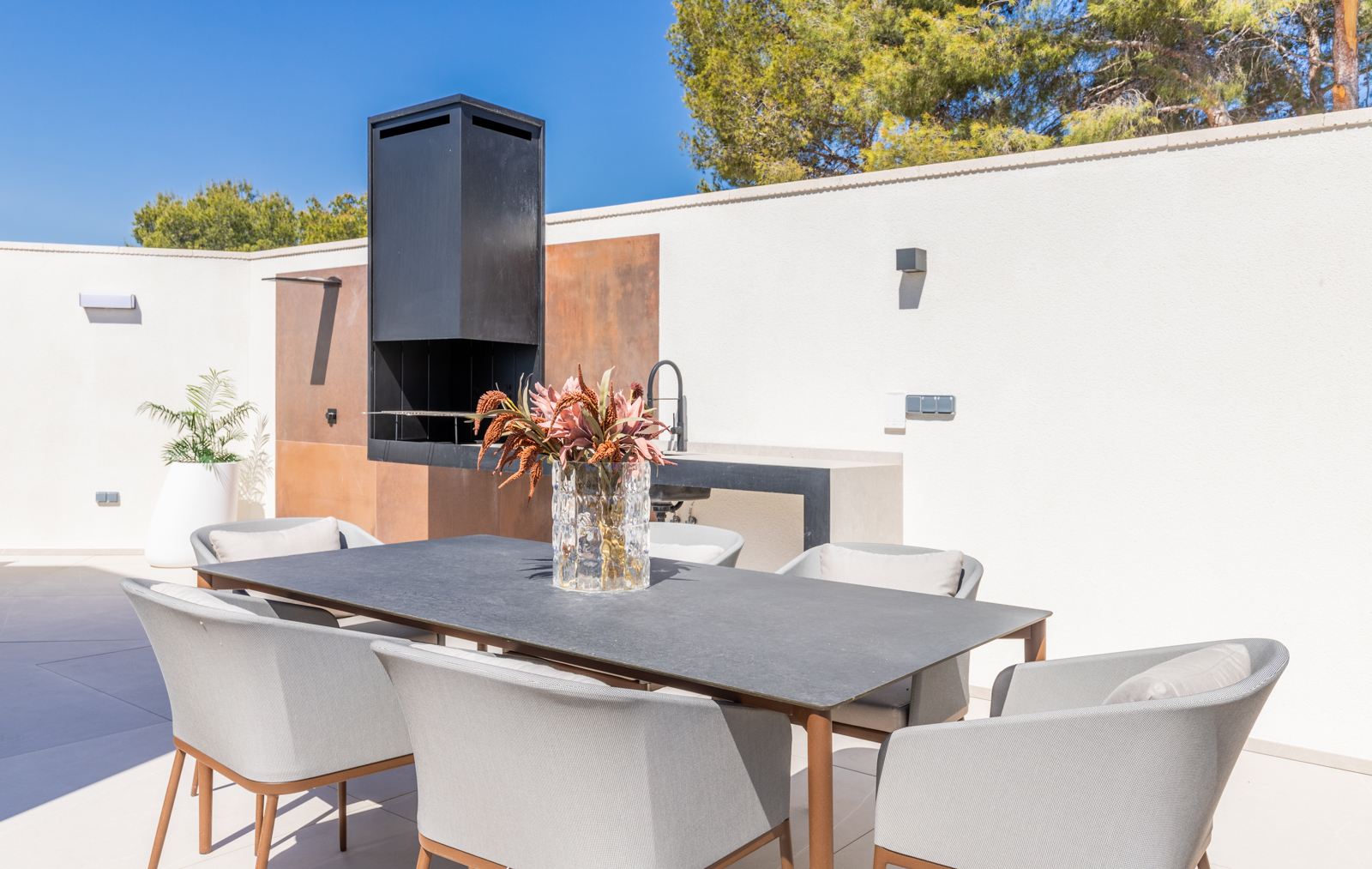 Detail of the outdoor barbecue area with dining table and gray chairs in La Nucia.