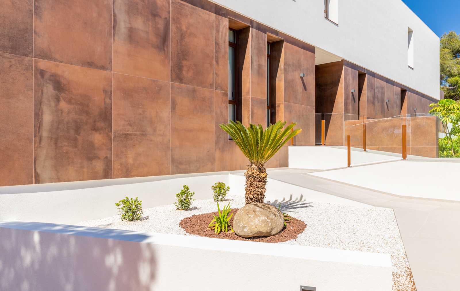 Front garden detail with rust-colored panel wall and access path.