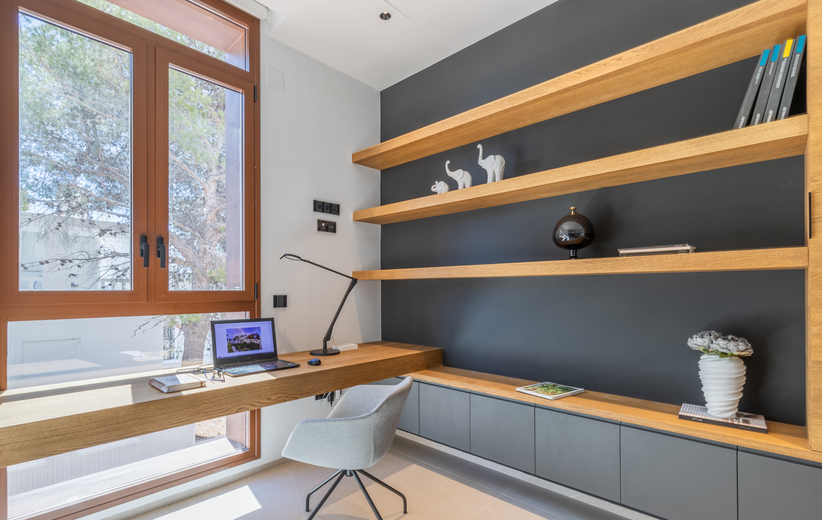 Home office featuring light wood shelving and built-in desk by the window.