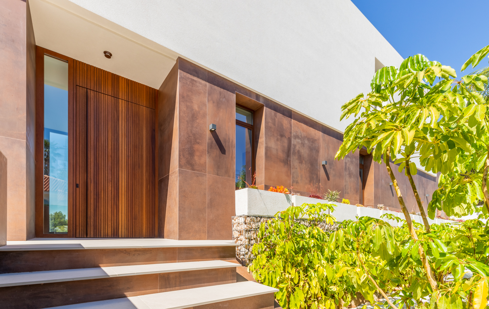 Modern entrance with vertical wood door and rust-colored ceramic cladding.