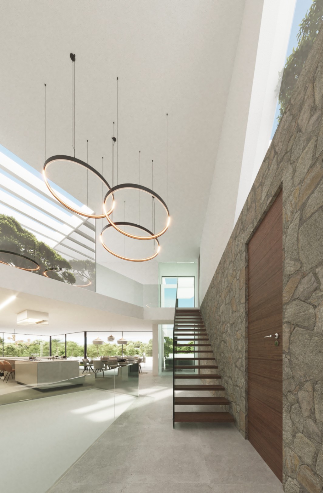 Double-height entrance hall featuring a natural stone wall, floating wooden staircase, and minimalist halo pendant lighting beneath a large architectural skylight.