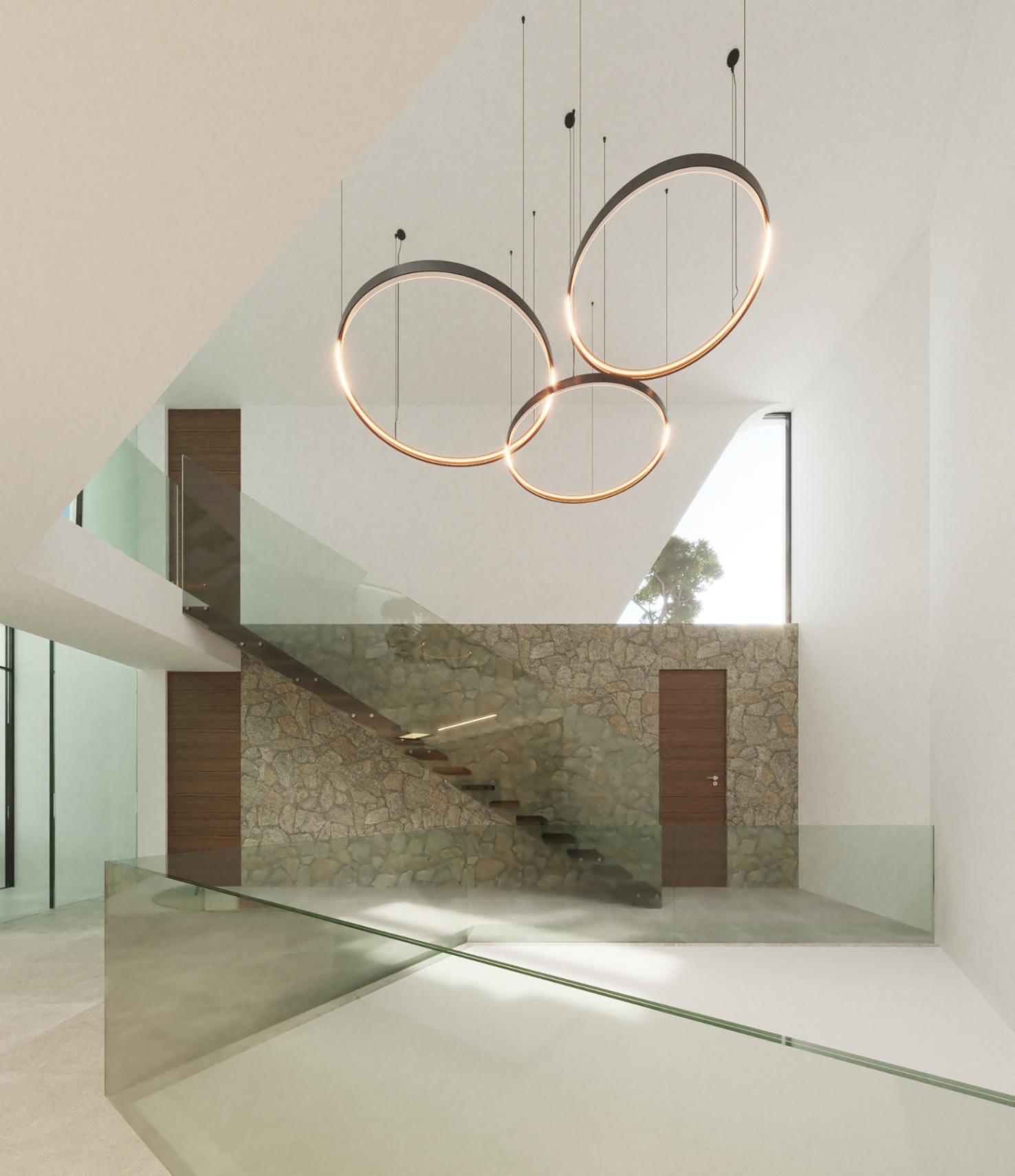 Floating staircase with wooden treads and glass balustrades, set against a natural stone feature wall with modern circular pendant lighting in a high-ceiling atrium.