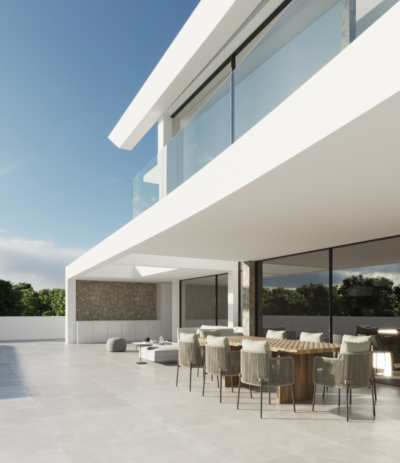 Outdoor terrace featuring a wooden dining set with woven chairs, set against minimalist white architecture, natural stone accents, and glass balcony railings.