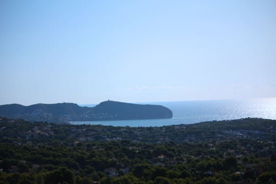Panoramic view from the property overlooking the Mediterranean Sea and the Moraira headland, framed by lush pine forests and residential areas.