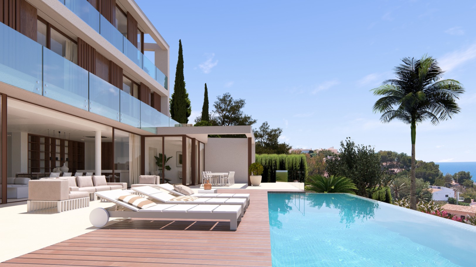 View of the infinity pool with wooden deck and sun loungers, overlooking the sea and lush greenery.