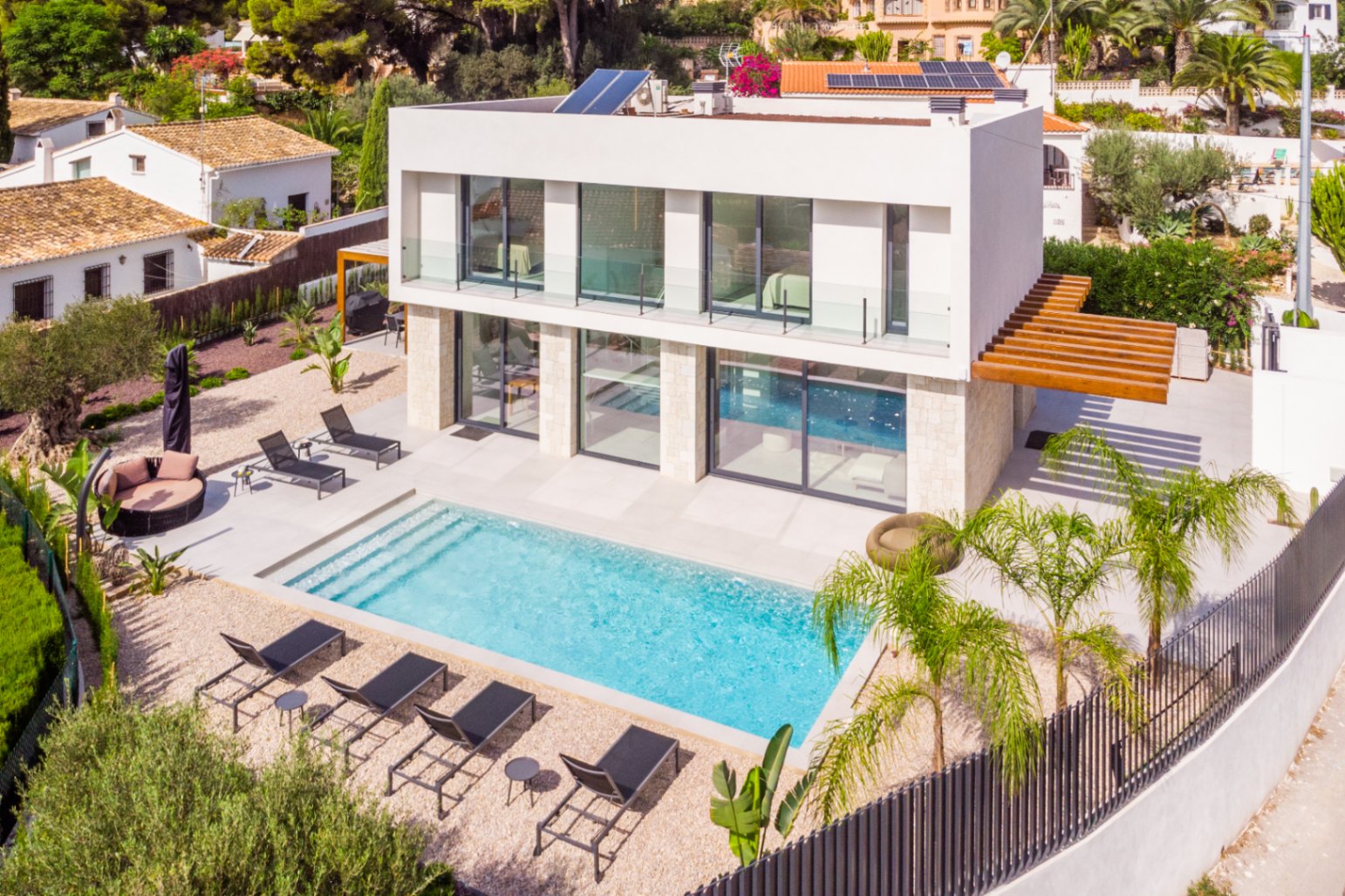 Aerial view of the villa featuring a turquoise pool, surrounded by sun loungers and light gravel.