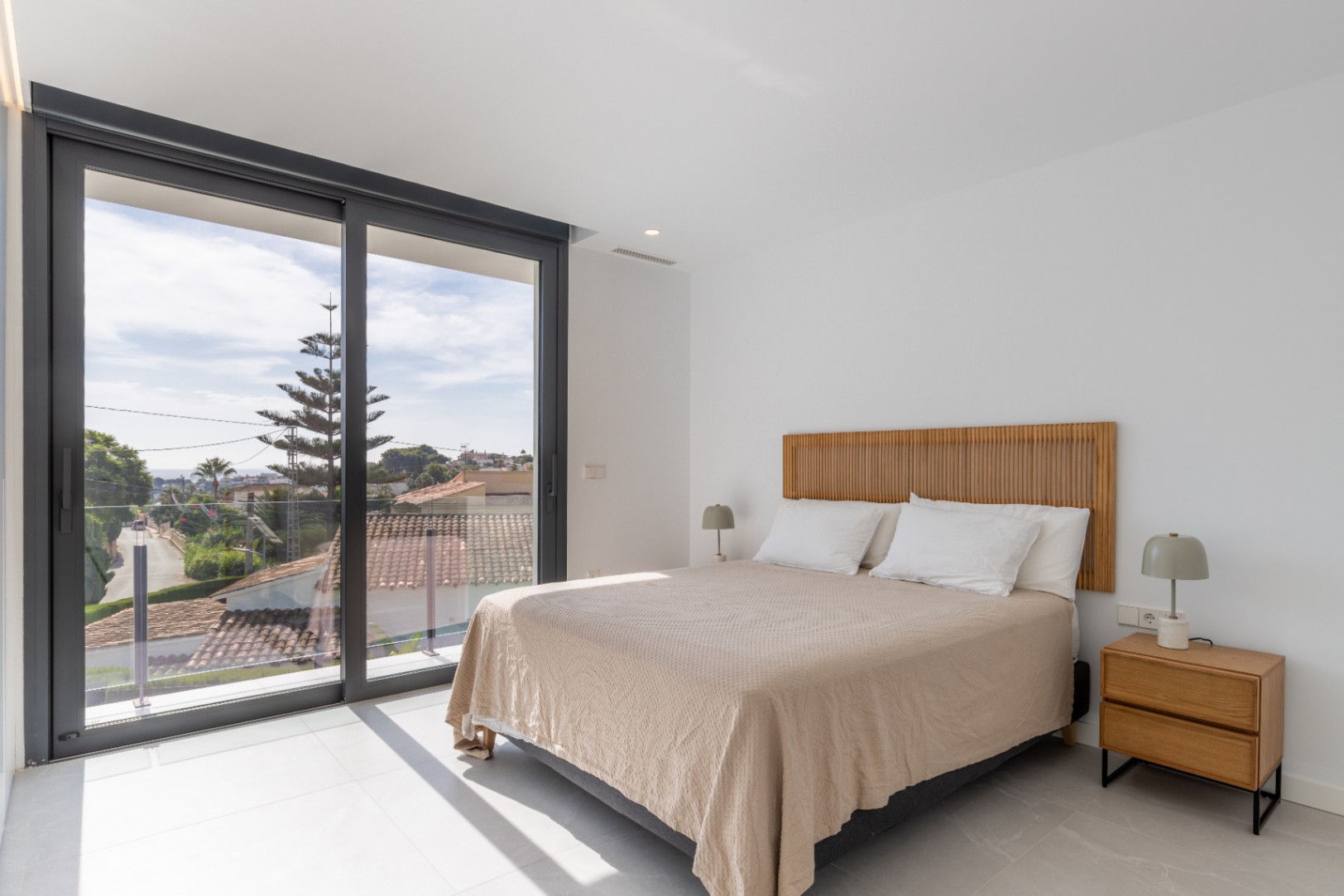 Bright bedroom featuring a double bed, wooden headboard, and exterior views.