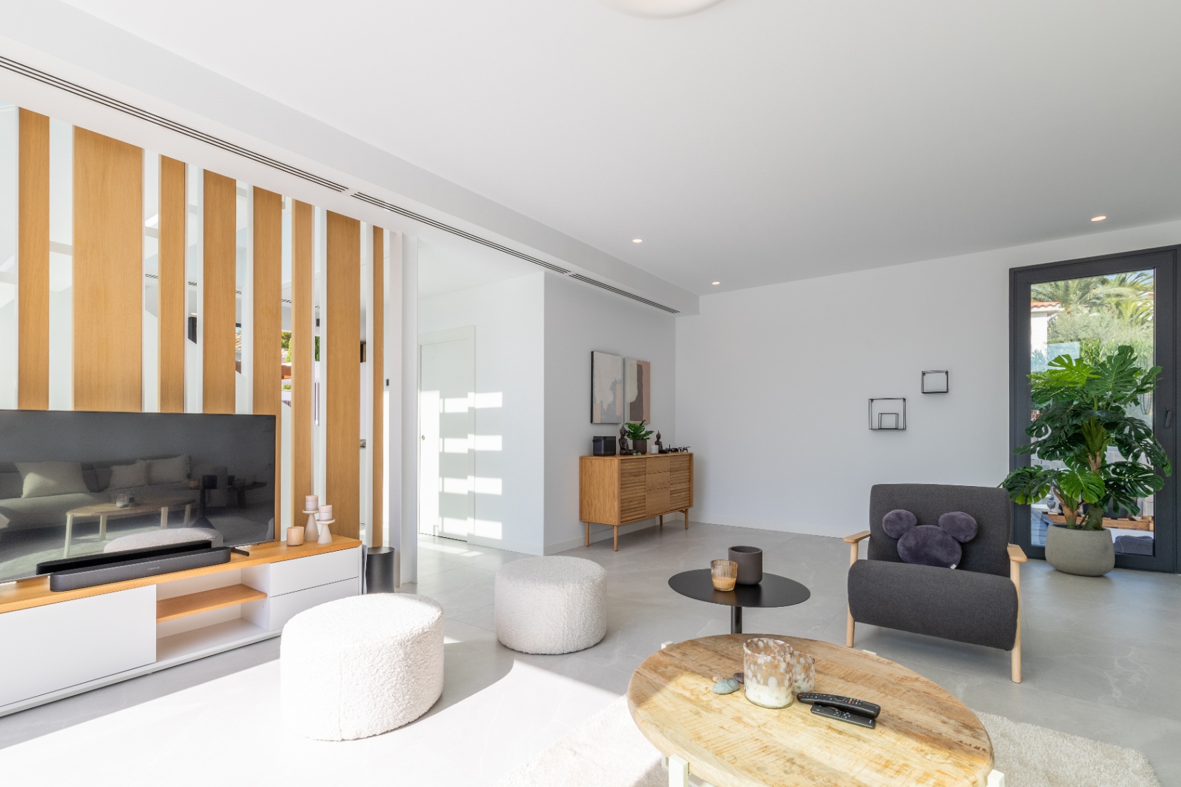 Bright living room featuring a wooden slat divider, modern furniture, and minimalist design touches.
