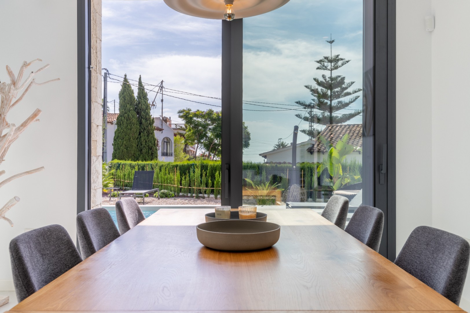 Dining room with wood table and view to the pool and fenced garden.