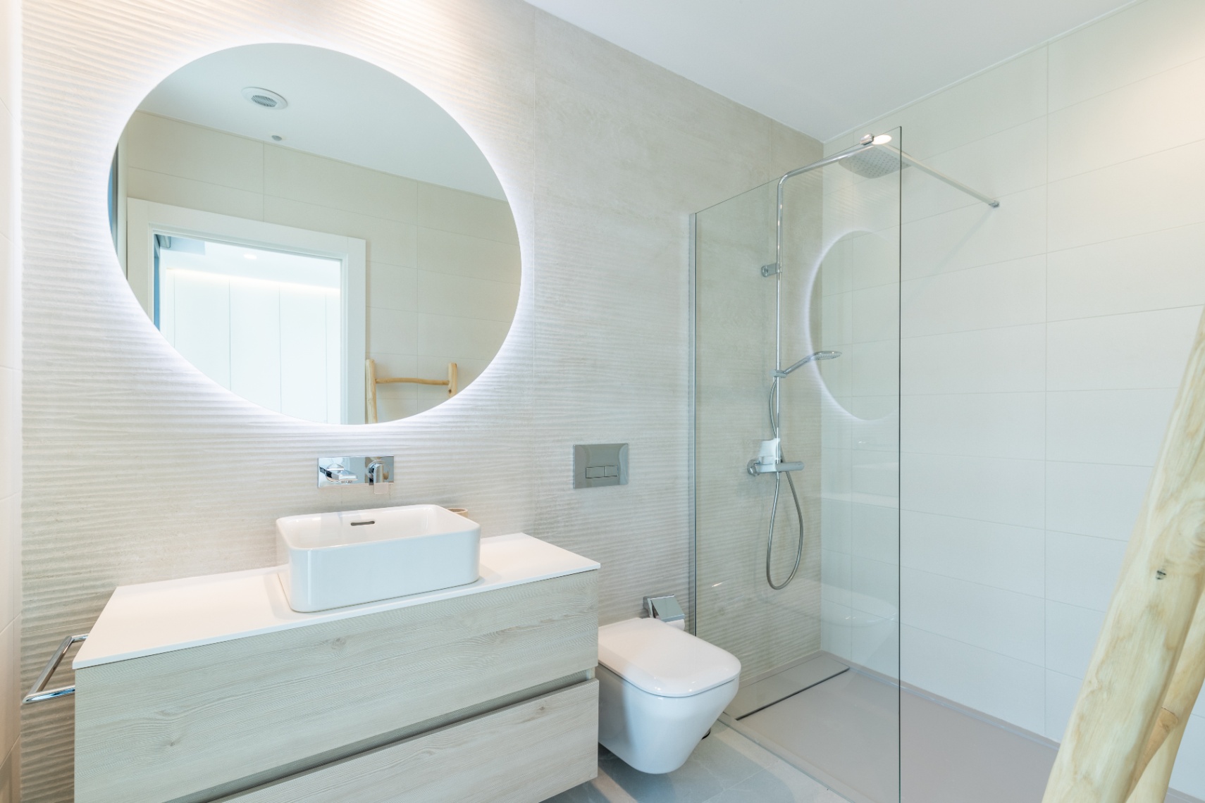 Modern bathroom featuring a square sink, backlit mirror, and glass-enclosed shower.