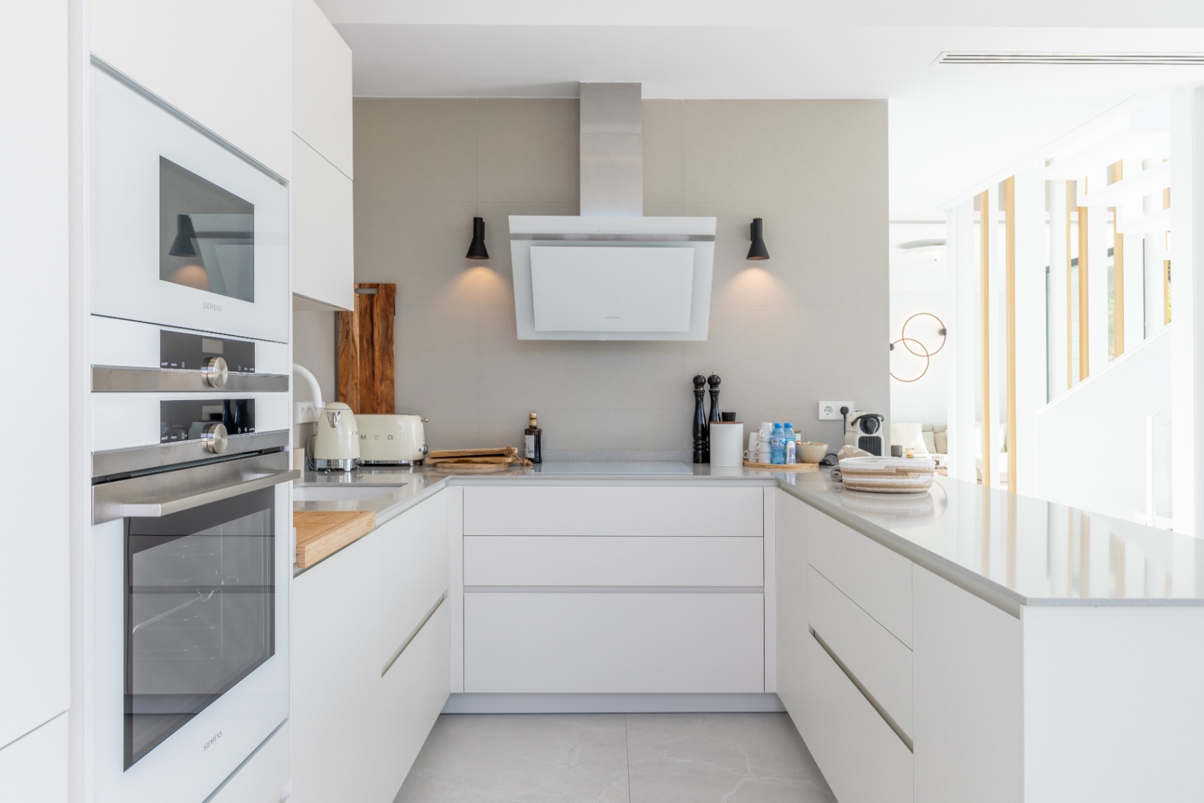 Modern kitchen featuring Siemens appliances, light stone countertops, and a minimalist extractor hood.