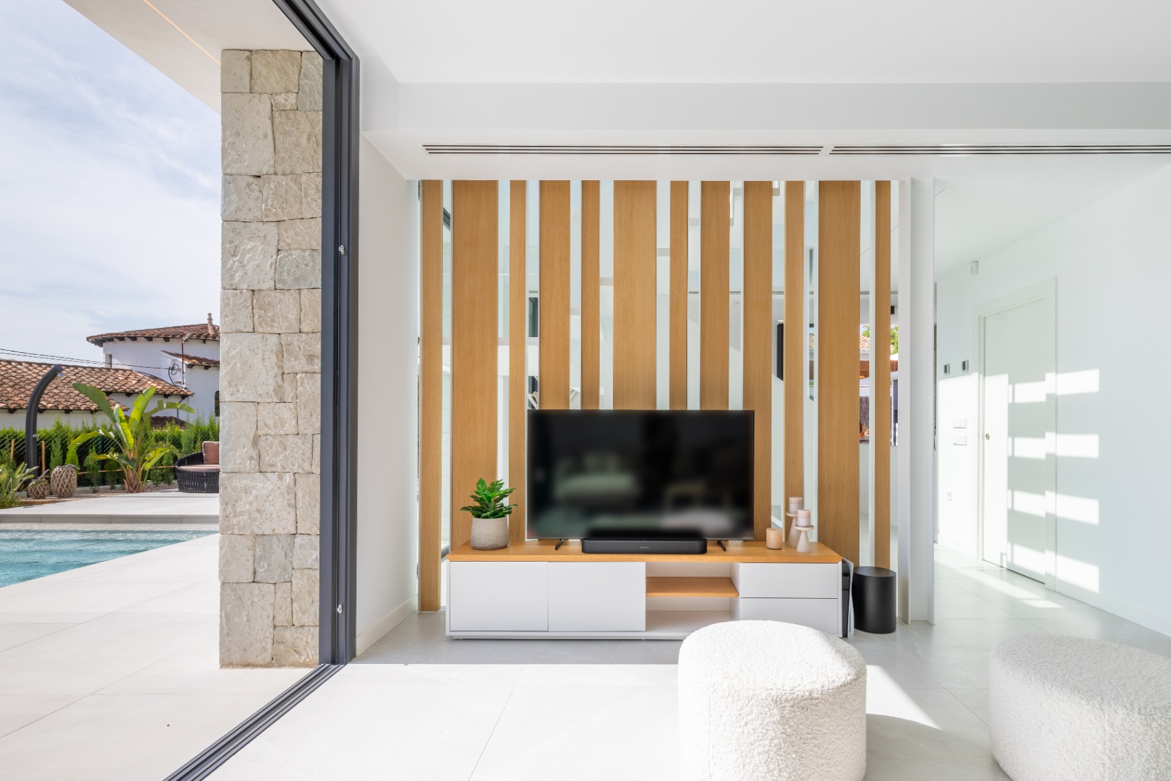 Modern living room featuring a TV stand and light wood screen. Access to the terrace with pool.