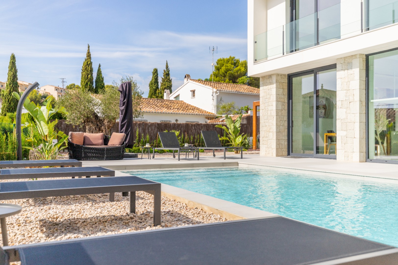 Pool view with gray sun loungers and outdoor lounge area featuring terracotta cushions.
