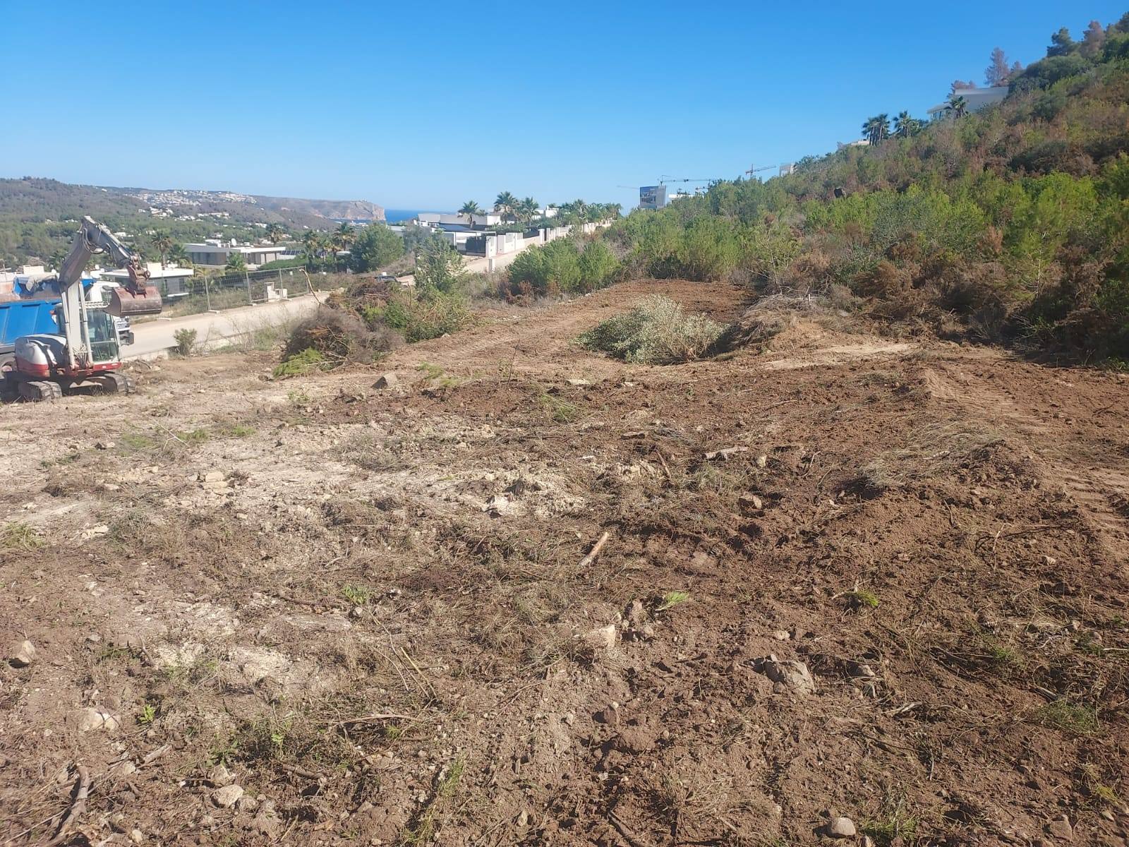 Land being prepared in Jávea with excavator and sea views.