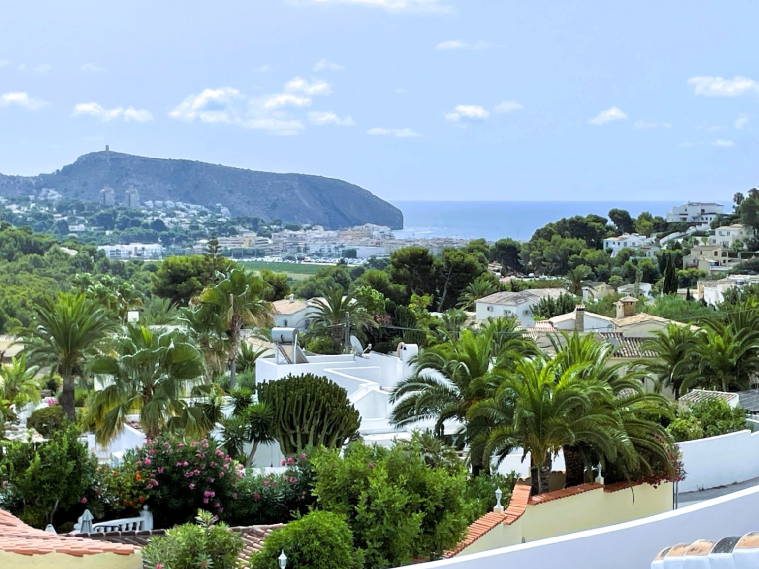 Elevated panoramic views overlooking the Moraira coastline, the Mediterranean Sea, and the Cap d'Or headland, framed by lush Mediterranean greenery.