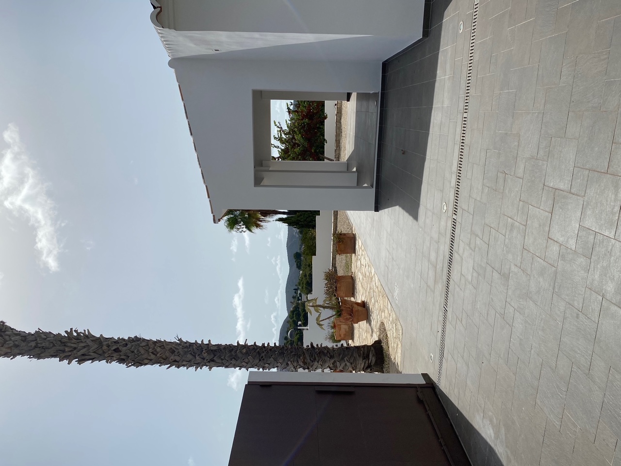 Exterior entrance featuring grey tiling, a metal gate, a palm tree, and a covered porch. Includes recessed ground lighting and clear mountain views.