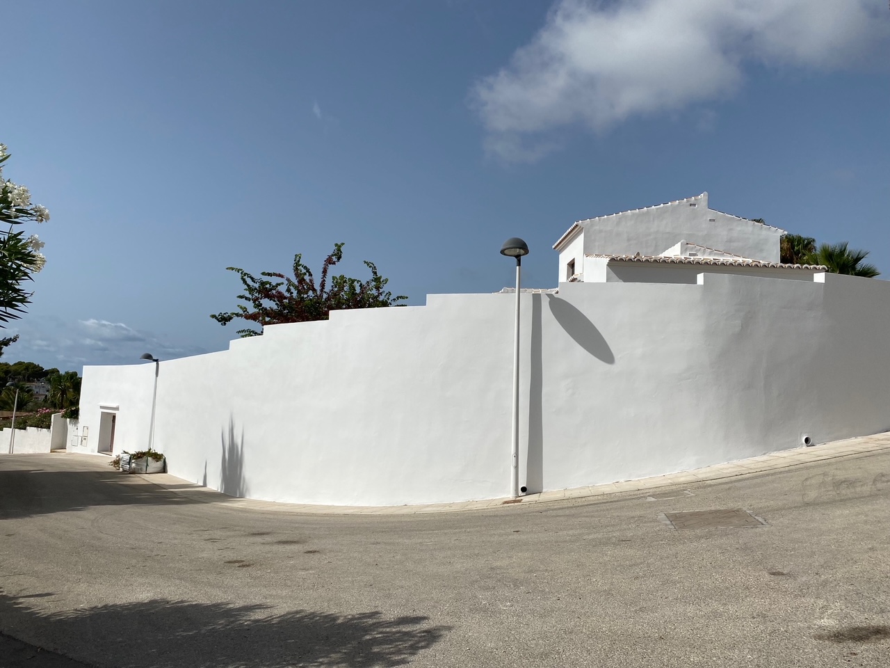 Exterior view showing the high, stepped white perimeter wall that ensures complete privacy and security for the villa from the quiet residential street.