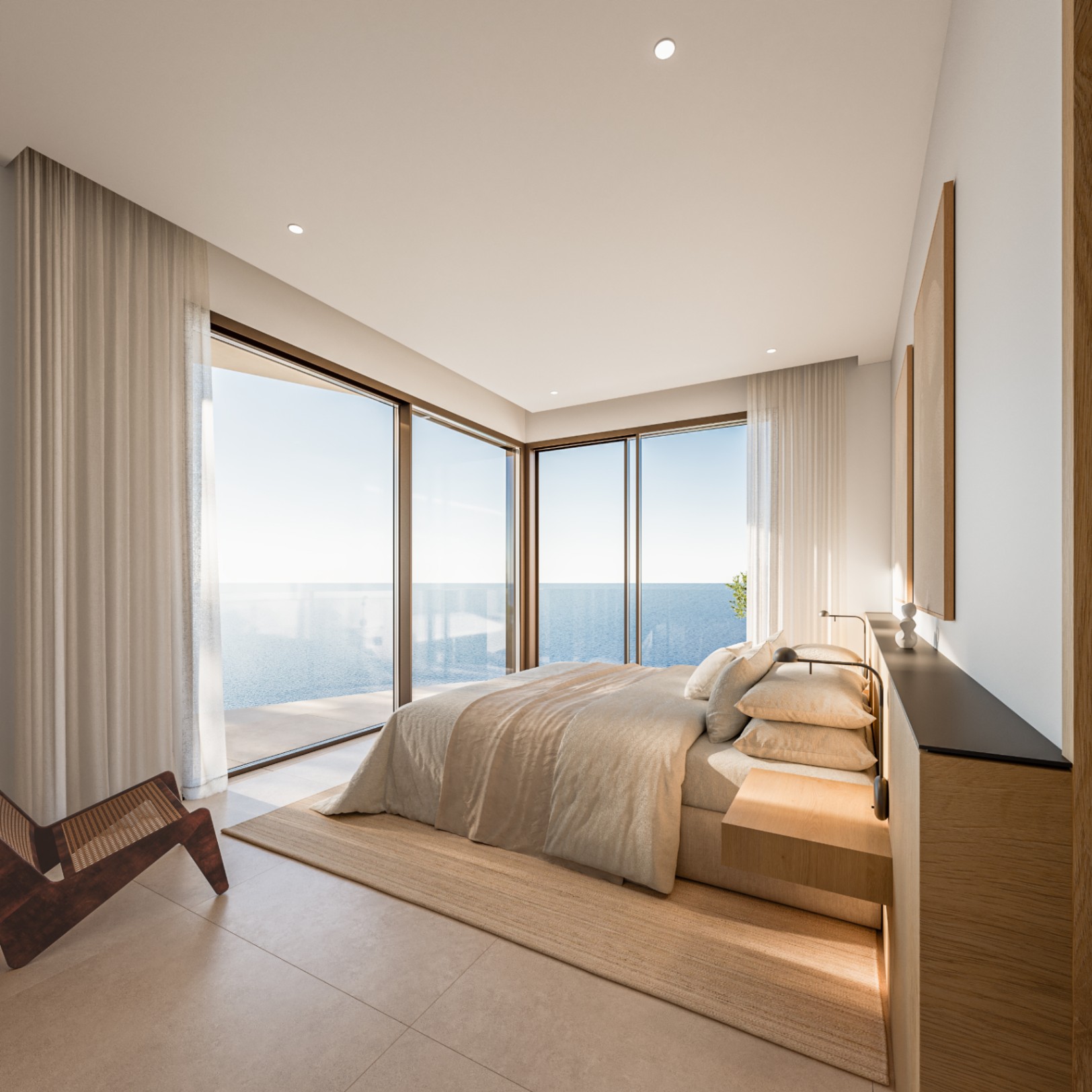 Master bedroom featuring floor-to-ceiling corner windows with Mediterranean views. Includes minimalist oak-toned cabinetry, a designer lounge chair, and recessed lighting.