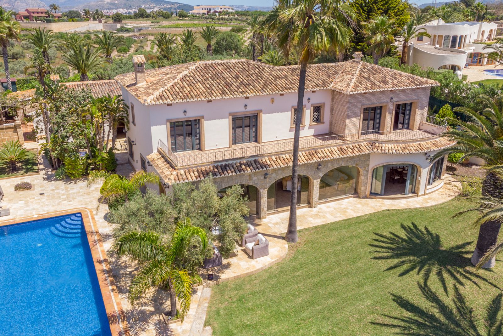 Aerial view of the villa featuring a pool, garden, and covered terrace with stone arches.