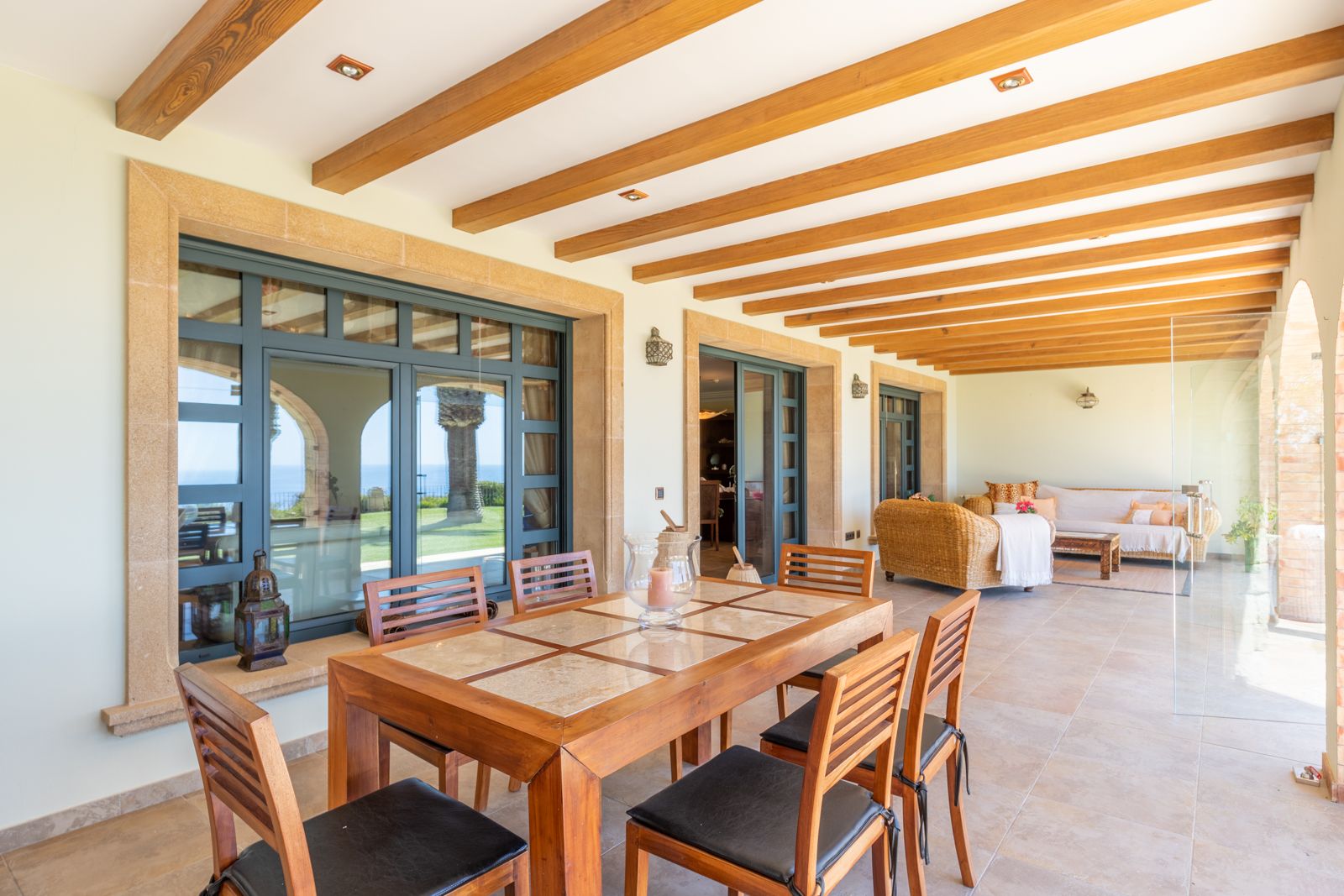 Covered outdoor dining area featuring wood beams, with garden and sea views.