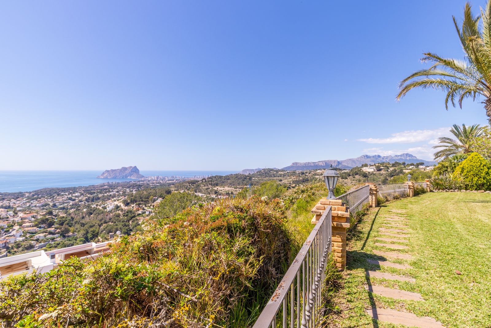 Panoramic view from the garden with a stone path and metal railing.