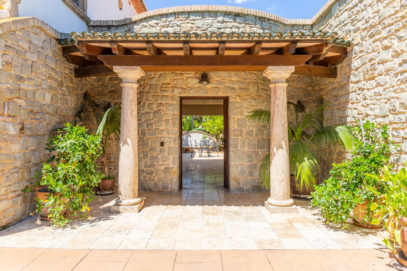 Portico entrance with stone columns and lush greenery.