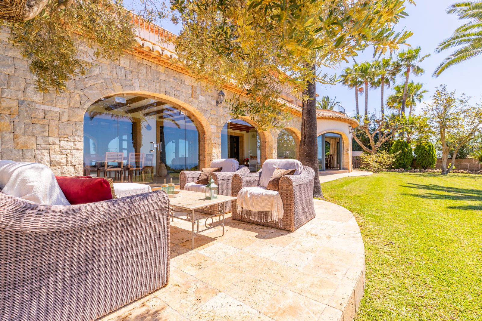 Terrace with wicker seating and stone arches overlooking the garden.