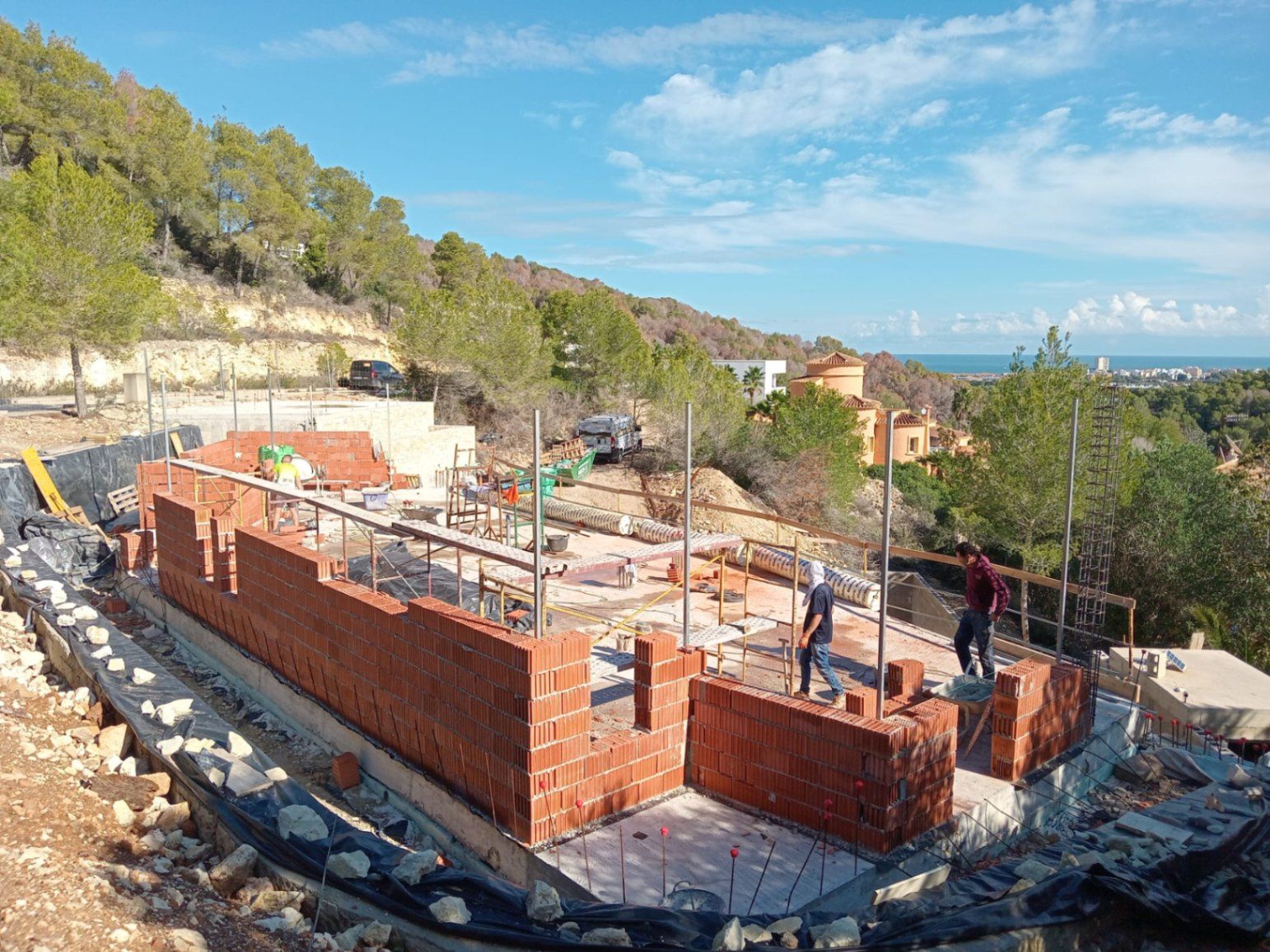 Initial construction phase of the villa in Jávea, featuring the brickwork of the main structure on an elevated plot with panoramic Mediterranean Sea views.