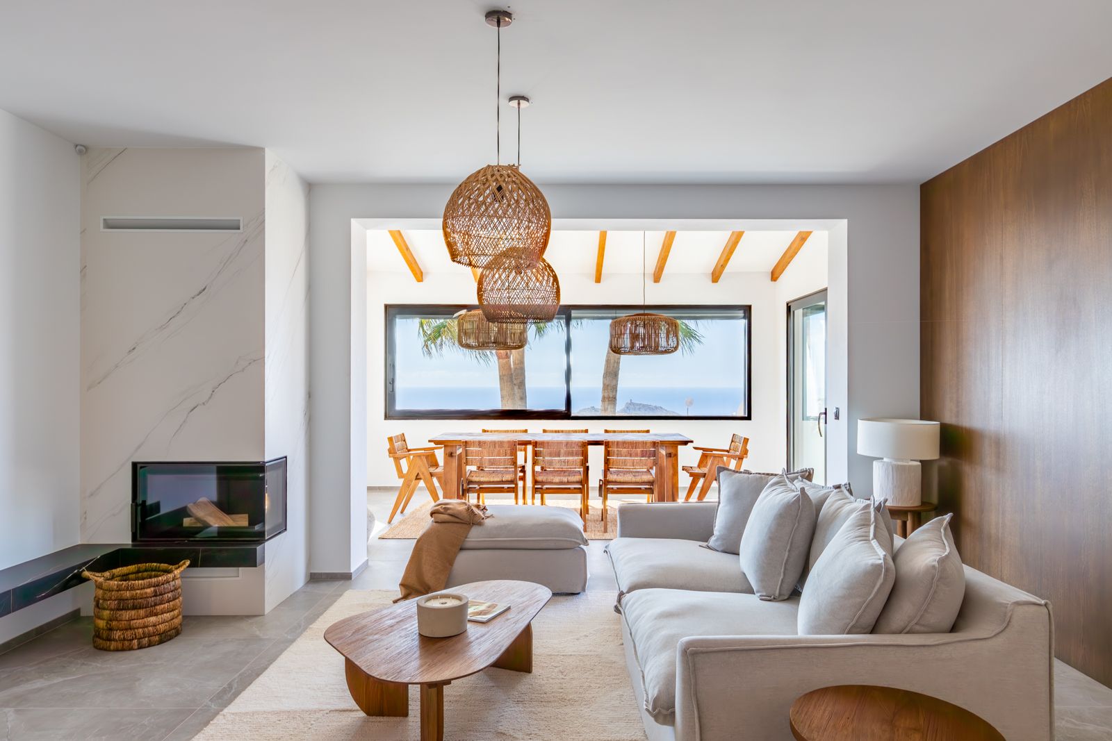 Living area featuring a sintered stone fireplace, natural oak wall paneling, and a dining space with Mediterranean sea views.