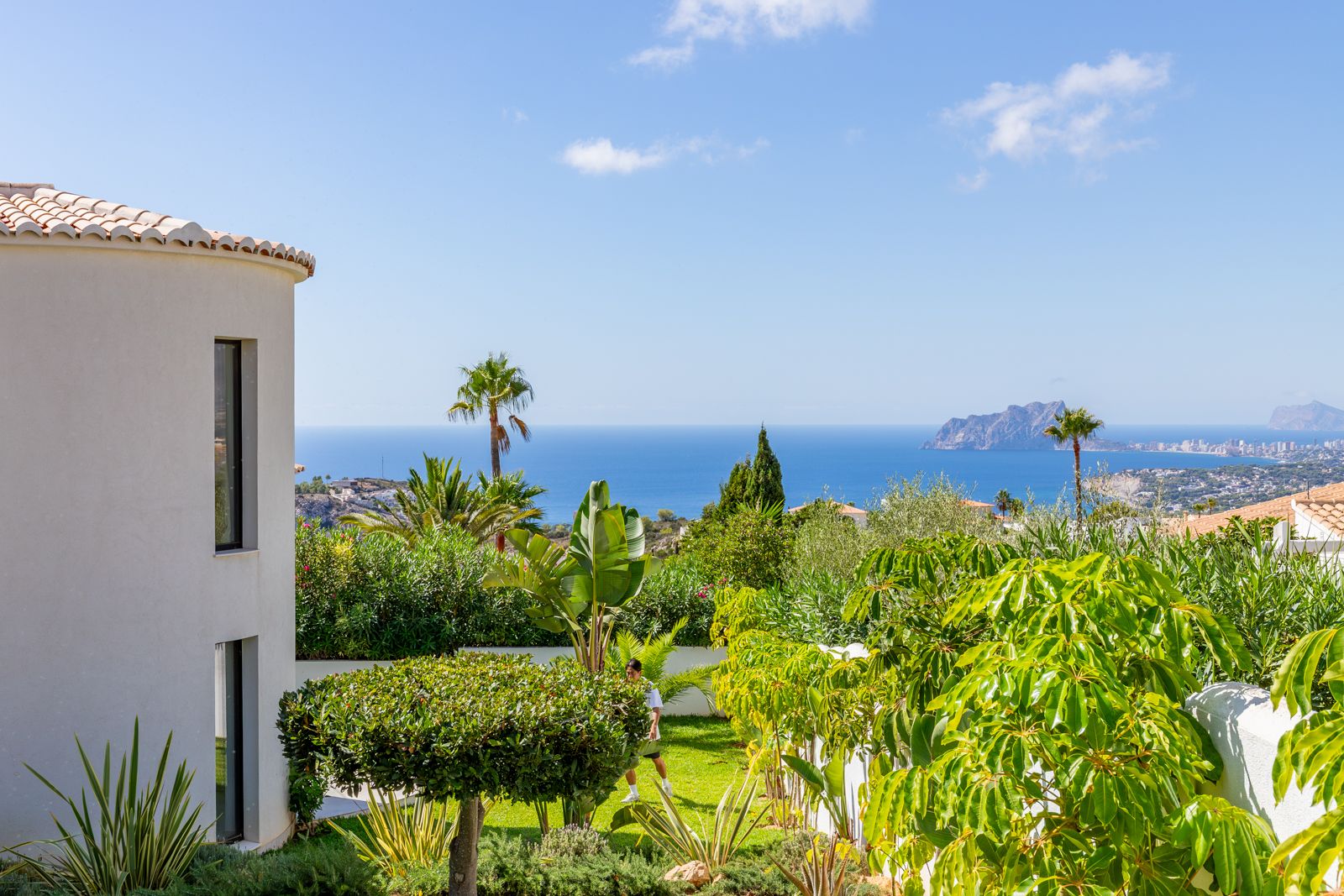 Panoramic views of the Mediterranean Sea and Peñón de Ifach from the landscaped garden surrounding the villa's curved modern facade.