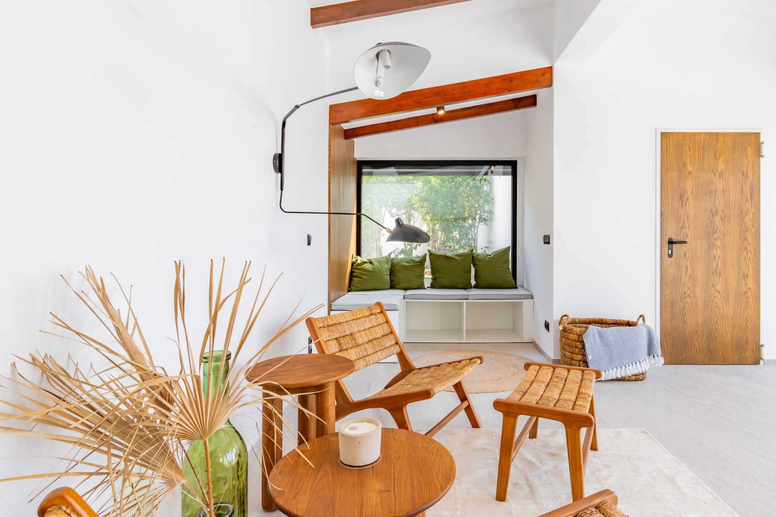 Reading nook featuring a built-in window seat, exposed wooden beams, and natural fiber furniture. Includes a designer wall lamp and a solid oak interior door.
