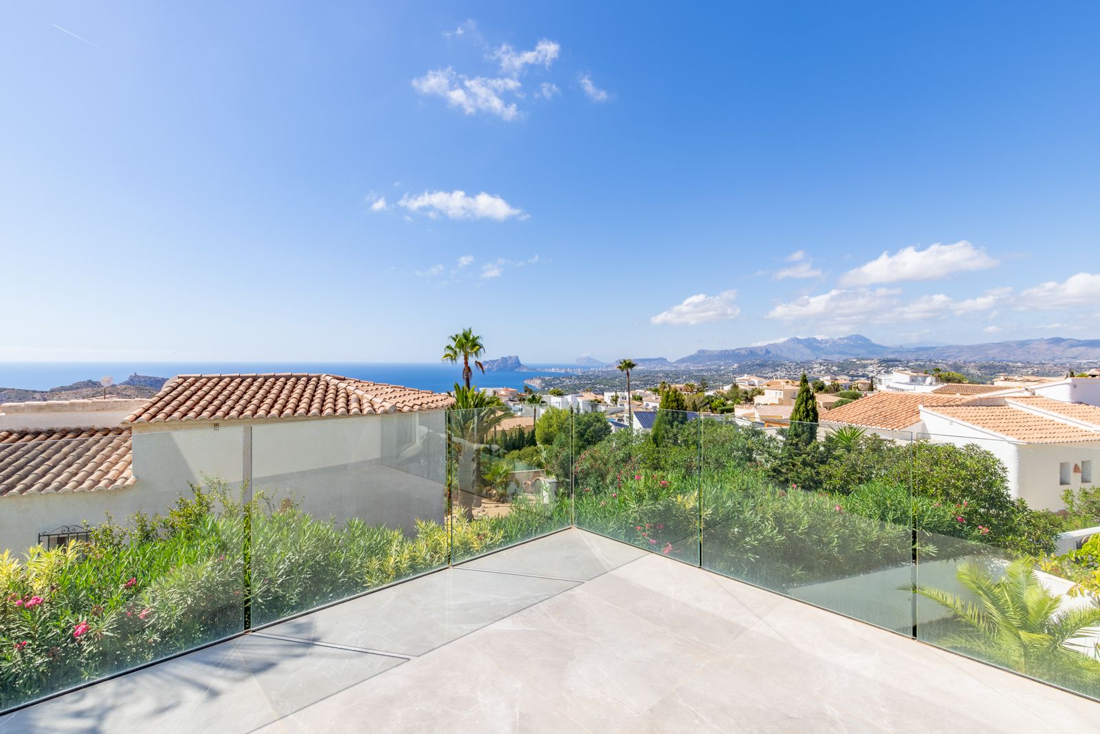 Upper terrace featuring large-format porcelain tiling and glass balustrades, providing panoramic views of the Mediterranean Sea and the Peñón de Ifach.