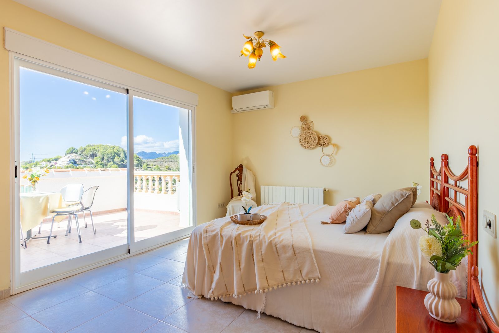 Bright bedroom featuring large sliding glass doors that open onto a private terrace. Equipped with air conditioning, central heating, and scenic mountain views.