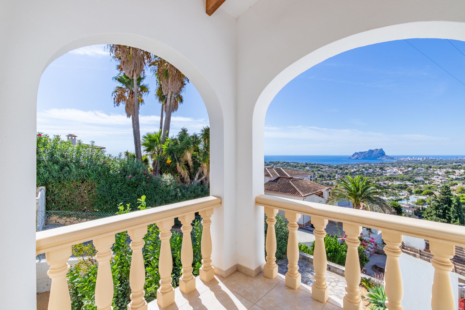 Covered terrace featuring white arches and a classic balustrade, offering panoramic views of the Mediterranean Sea and the Peñón de Ifach.